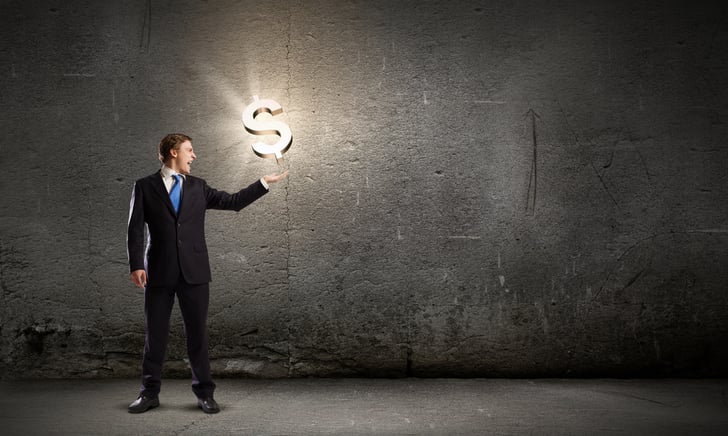 Businessman in suit holding dollar sign in palm
